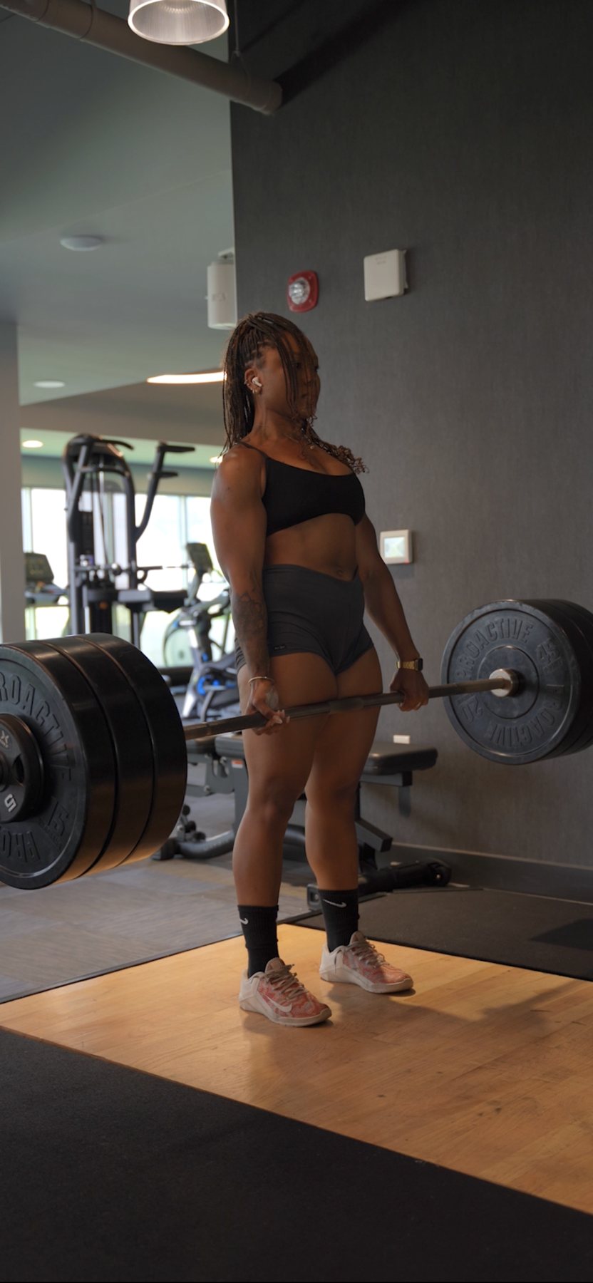 Morgan standing tall at the top of a heavy barbell deadlift in the gym